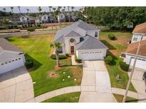 Well-maintained two-story home with manicured lawn, mature landscaping, and a spacious driveway to an attached two-car garage at 8217 Fan Palm Way, Kissimmee, FL 34747