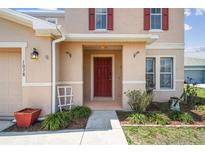 Inviting front entrance with a covered porch, red door and manicured landscaping at 1038 Sabine Pl, Kissimmee, FL 34759