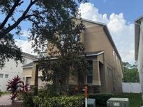 Side view of a two-story home with beige stucco, complemented by lush greenery and a partly cloudy sky at 12867 Woodmere Close Dr, Windermere, FL 34786