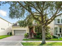 Charming home featuring a two-car garage, brick driveway, and mature landscaping at 12867 Woodmere Close Dr, Windermere, FL 34786