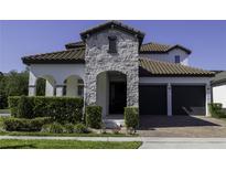 Beautiful home exterior featuring a stone facade, arched entry, and a two-car garage with a brick driveway at 15079 Guava Bay Dr, Winter Garden, FL 34787