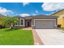 Charming single-story home featuring a well-manicured lawn, brick pathway, and attached two-car garage at 2040 Patriot Way, St Cloud, FL 34769