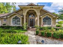 Inviting front entrance featuring an arched doorway, columns, and lush landscaping at 154 Academy Oaks Pl, Altamonte Springs, FL 32714
