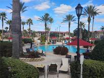Resort-style pool area with palm trees, comfortable lounge chairs, and vibrant red umbrellas at 247 Verona Ave, Davenport, FL 33897