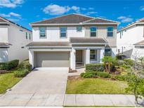 Inviting two-story home featuring a two-car garage, lush landscaping, and a welcoming front entrance at 438 Marcello Blvd, Kissimmee, FL 34746