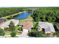 Aerial view of a single-story home featuring lush landscaping and a tranquil lake backdrop at 650 Portofino Drive, Poinciana, FL 34759