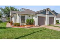 Charming single-story home features a well-manicured lawn and an attached two-car garage with mature flowering landscaping at 98 Lakepointe Cir, Kissimmee, FL 34743