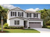 Charming two-story home with gray siding, black shutters, a two-car garage, and manicured landscaping at 183 Flag Lilly Ln, Umatilla, FL 32784
