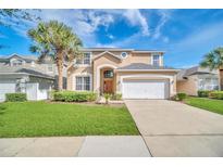 Charming two-story home featuring a well-manicured lawn, attached garage, and beautiful landscaping at 2632 Emerald Island Blvd, Kissimmee, FL 34747