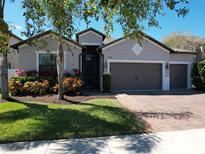 Charming single-story home with a three-car garage, landscaped yard, and brick paved driveway at 2888 Spring Breeze Way, Kissimmee, FL 34744