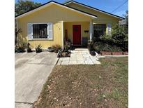 Charming yellow single-story home featuring a red front door, white shutters, and well-maintained landscaping at 716 Grove Ave, Orlando, FL 32805