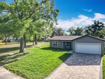 Charming single-Gathering home featuring a brick driveway, well-manicured lawn, and an attached two-car garage at 7823 Bell Blvd, Orlando, FL 32810
