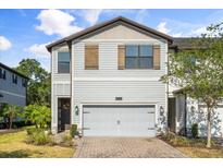 Charming two-story townhome featuring a paver drive, two-car garage and inviting entryway with decorative wreath at 11120 Whistling Pine Way, Orlando, FL 32832