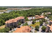 Expansive aerial view of the condo community with a pool, mature trees, and highway access at 1375 Tuscana Ln # 1207, Davenport, FL 33896