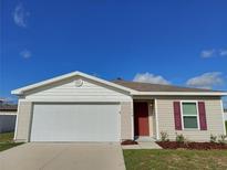 Charming single-Gathering home with a 2-car garage, red front door, and well-maintained lawn at 158 Violet Ct, Poinciana, FL 34759