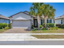 Charming single-story home with a brick driveway, two-car garage, and tropical palm trees at 17324 Bracken Fern Ln, Clermont, FL 34714