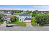 Aerial view of home and surrounding lot with lake and golf course views in the community at 1976 The Oaks Blvd, Kissimmee, FL 34746