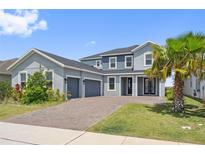 Charming two-story home featuring a three-car garage, brick driveway, and well-manicured lawn at 2110 Old Hollow Ln, Clermont, FL 34715
