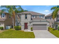 Two-story home with neutral paint, attached two-car garage and mature palm trees enhancing the front yard at 253 Aldridge Ln, Davenport, FL 33897