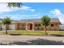 Inviting single-story home featuring a bright red front door and a well-manicured lawn at 3122 Eleuthera Ln, Orlando, FL 32827