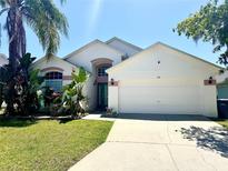 Charming single-Gathering home featuring a well-manicured lawn, inviting entrance, and attached two-car garage at 314 Saddle Ridge Dr, Davenport, FL 33896