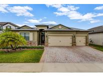 Charming one-story home featuring a three-car garage, decorative stone accents, and a brick paved driveway at 4337 Summer Breeze Way, Kissimmee, FL 34744