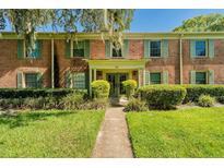 Charming two-story brick building featuring traditional architecture, vibrant green shutters, and well-manicured landscaping at 525 Georgetown Dr # D, Casselberry, FL 32707