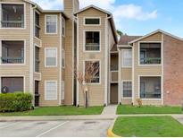 Tan Condo with green yard and awning; easy parking and a sidewalk to the front entrance at 5501 Rosebriar Way # 111, Orlando, FL 32822