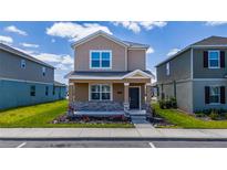 Charming two-story home with stone accents, landscaped front yard, and inviting covered porch at 6452 Sprucepine Ln, St Cloud, FL 34771