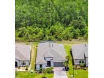 New construction home featuring a two-car garage, a well-manicured lawn, and lush green landscaping at 684 San Augusto Dr, Poinciana, FL 34759