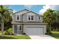 Charming two-story home featuring gray siding, a two-car garage, and a lush green lawn at 733 Lake Dell Rd, Dundee, FL 33838