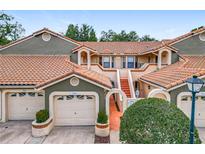 Inviting two-story townhome showcasing a red tile roof, stucco facade, and well-maintained landscaping at 7806 Sugar Brook Ct # 7806, Orlando, FL 32819