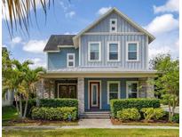 Charming two-story home with a well-manicured lawn, stone accents, and a welcoming covered front porch at 7878 Greengard St, Orlando, FL 32827