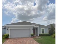 Charming single-story home with a well-manicured lawn and beautiful brick paved driveway at 878 Benjamin Trl, Davenport, FL 33837
