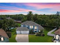 Stunning two-story home featuring a three-car garage, lush landscaping, and a beautiful dusk sky at 13044 Lakeshore Grove Dr, Winter Garden, FL 34787