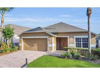 Charming one-story home with a well-maintained lawn, brick driveway, and attached two-car garage at 147 Bridgewater Dr, Davenport, FL 33897