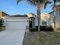 Charming single-story home featuring a gray facade, two-car garage, and well-maintained landscaping at 1574 Thetford Cir, Orlando, FL 32824