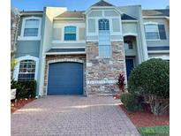 Two-story townhome featuring a brick driveway, attached garage, and stone facade at 15851 Woodland Spring Ct, Orlando, FL 32828