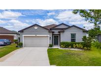 Charming one-story home with a manicured lawn, neutral paint, and an attached two-car garage on a sunny day at 1821 Cayman Cove St., St Cloud, FL 34772