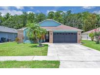 Charming single-story home with blue accents, a well-manicured lawn, and a two-car garage at 2398 Queenswood Cir, Kissimmee, FL 34743