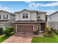 Two-story home with a brick paver driveway, two car garage, neutral siding, and manicured landscaping at 3084 Slough Creek Dr, Kissimmee, FL 34744