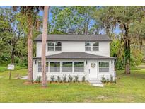 Charming two-story home with a white exterior, well-manicured lawn, and a welcoming front entrance at 5851 Se Drew Rd, Belleview, FL 34420