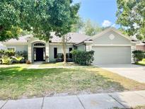 Charming single-story home featuring a well-maintained lawn, mature trees and a two car garage, showcasing curb appeal at 671 Carey Way, Orlando, FL 32825