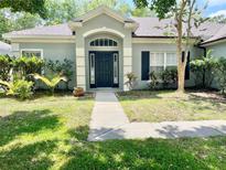 Inviting single-Gathering home with neutral exterior paint, arched entry and well-manicured front lawn, exemplifying suburban charm at 671 Carey Way, Orlando, FL 32825