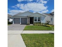 Charming single-story home with a well-manicured lawn, gray garage doors, and a beautiful stone facade at 19235 Allium Pl, Orlando, FL 32827