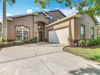 Charming stucco home featuring a two-car garage, well-manicured landscaping, and a welcoming front entrance at 207 Bailey Cir, Davenport, FL 33897