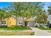 Charming two-story home features a well-manicured lawn, a two-car garage, and mature trees offering ample shade at 2985 Banana Palm Dr, Kissimmee, FL 34747