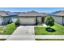 Charming single-story home featuring a well-maintained lawn, two-car garage, and solar panels for energy efficiency at 5816 Beefmaster Rd, St Cloud, FL 34771