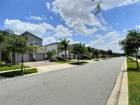 Charming street view showcasing well-maintained homes, manicured lawns, and beautiful landscaping under a sunny sky at 703 Ocean Course Ave, Davenport, FL 33896