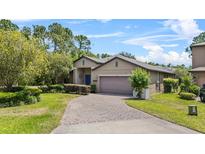 Inviting single-story home featuring a well-manicured lawn and a brick driveway at 1103 Cypress Pointe Blvd, Davenport, FL 33896